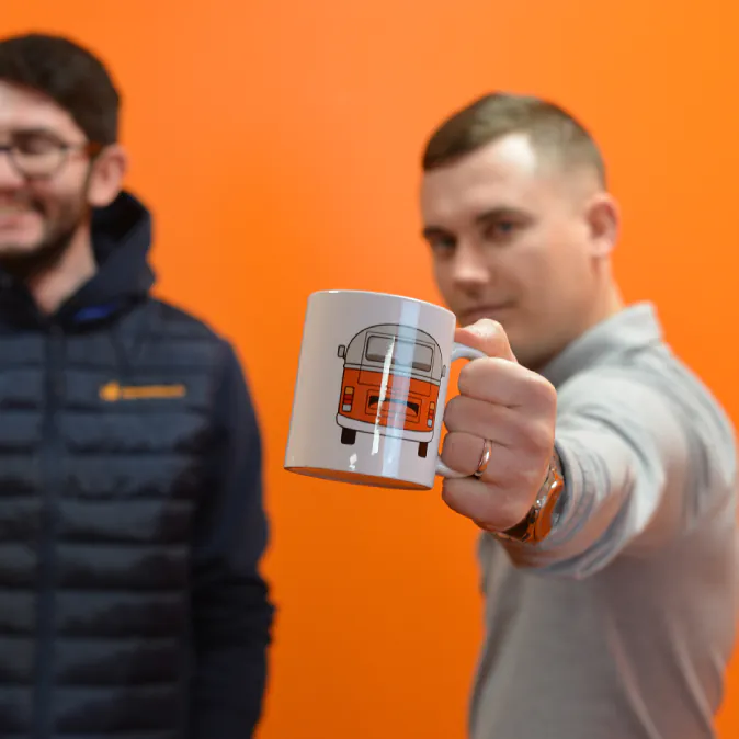 Photo d'un mug Clementine tenu par un collaborateur dans une salle de réunion orange